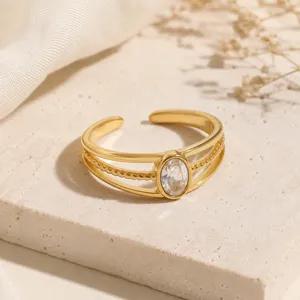 Primo piano di un anello regolabile in acciaio dorato con una pietra di zircone ovale.