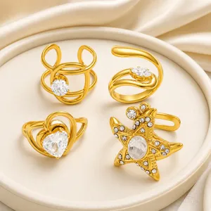 Detalle de cuatro anillos de acero inoxidable dorados con grandes circonitas de corazón y estrella