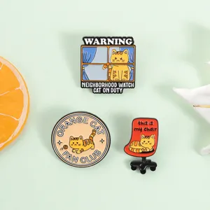 Detailopname van grappige oranje katten emaille speldjes met humoristische Engelse tekst