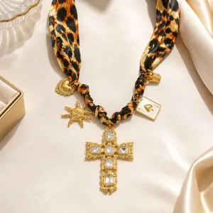 Detailed view of leopard scarf necklace featuring an ornate gold crystal cross pendant.