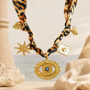 Detail view of leopard print silk scarf necklace with golden evil eye and charms