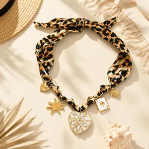 Close-up of leopard print scarf necklace with large heart locket and vintage sun charms