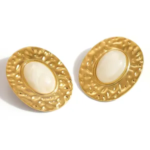 Close-up detail of retro hammered texture gold-plated earrings with smooth cream resin inlay