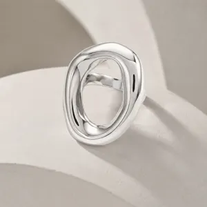 Dettaglio macro di un anello ovale geometrico irregolare in acciaio inossidabile lucido.
