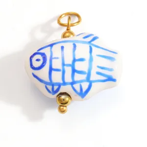 Gros plan d'un pendentif en forme de poisson blanc et bleu avec des anneaux dorés