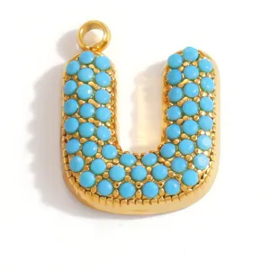 Dettaglio del ciondolo lettera U placcato oro con pietre turchesi blu per gioielli DIY.