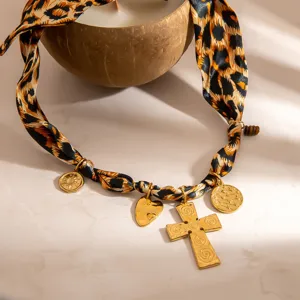 Detailed view of leopard print silk scarf necklace with gold cross and heart charms