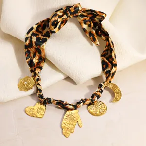 Close-up of a leopard print scarf necklace with gold charms in warm Maillard style