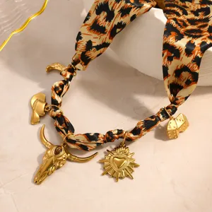 Macro view of leopard print silk scarf necklace with golden heart and bull skull charms
