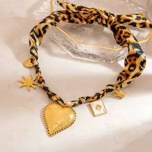 Close-up of leopard print silk scarf necklace with vintage heart and sun charms.