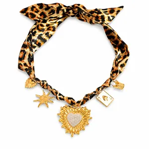 Elegant leopard print silk scarf necklace with gold-plated heart and sun charms detail.
