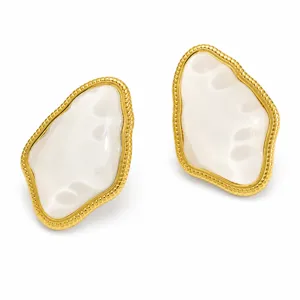 Close-up of vintage irregular geometric gold-plated earrings with white resin inlay