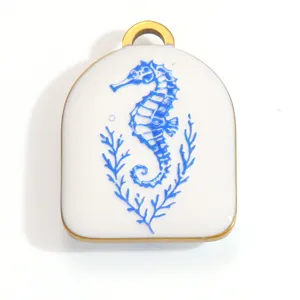 Macro detail view of a white enamel pendant featuring a blue seahorse and coral design
