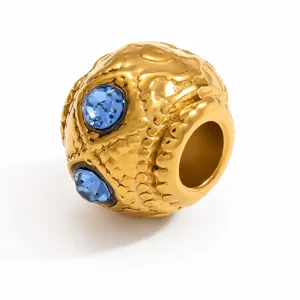 Dettaglio macro di una perla distanziatrice in acciaio inossidabile dorato con cristalli blu