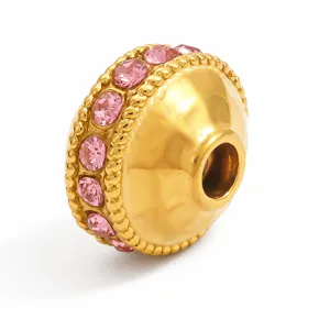 Dettaglio di una perla distanziatrice in acciaio dorato con strass rosa incastonati.