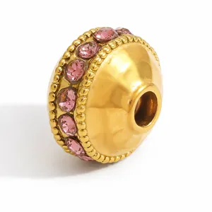 Dettaglio macro di un distanziatore in acciaio inossidabile dorato con cristalli rosa