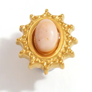 Detailed macro view of a sun-shaped gold decorative charm with a pale pink oval stone