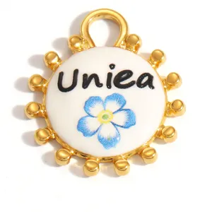 Macro detail of a white enamel sunflower pendant with a blue flower and Uniea text.