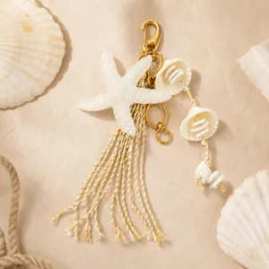 Détail d'un bijou de sac style marin avec une étoile de mer blanche et un pompon doré