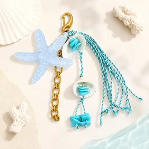 Détail du bijou de sac thème océan avec étoile de mer bleue, chaîne or et franges.