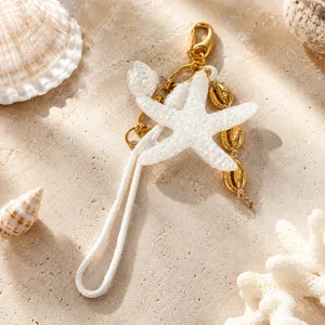 Vue détaillée de l'étoile de mer scintillante et des breloques coquillages dorées sur le sac