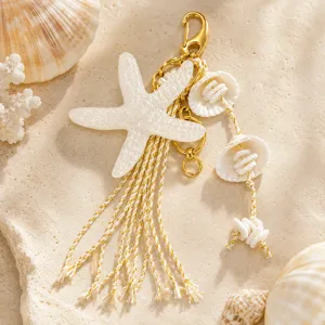 Gros plan d'un bijou de sac étoile de mer avec glands blancs et détails de coquillages dorés.