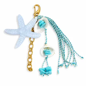 Détail d'un bijou de sac sur le thème marin avec étoile de mer bleue, coquillages et pompons