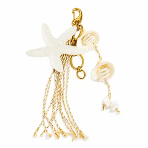 Détail d'un bijou de sac étoile de mer blanche nautique avec pompons dorés et coquillages
