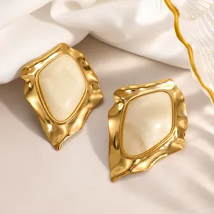 Macro view of irregular vintage geometric earrings with gold finish and cream resin center