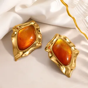 Macro view of vintage irregular gold-plated stainless steel earrings with amber resin