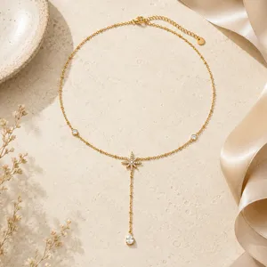 Detail view of a gold titanium steel necklace with an eight-pointed star and zircon drop.