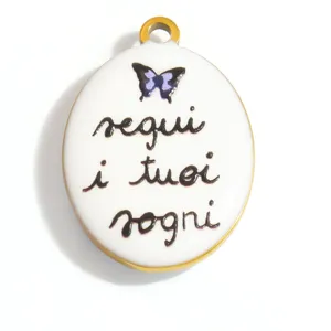 Dettaglio del ciondolo ovale in acciaio al titanio con scritta 'segui i tuoi sogni' e farfalla