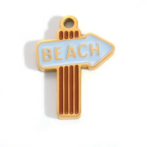 Macro view of a gold-plated stainless steel beach sign pendant with blue enamel.