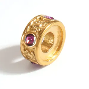 Macro detail showing textured gold finish and purple crystal inlay on a jewelry bead
