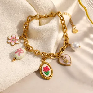 Macro detail of a gold-plated stainless steel charm bracelet with floral and heart pendants