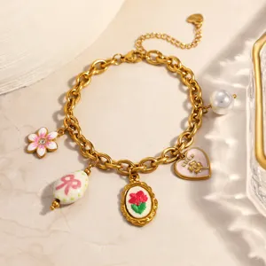 Detail of gold stainless steel charm bracelet with flower, heart, and pearl pendants