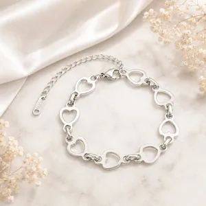 Détail d'un bracelet en acier inoxydable avec maillons en cœur sur fond marbre