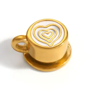 Macro detail of a gold coffee cup charm with heart latte art pattern