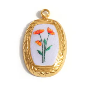 Macro view of gold stainless steel oval pendant with painted orange floral design