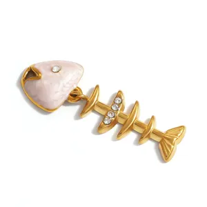 Detailed close-up of a golden fishbone pendant with pink enamel and crystals