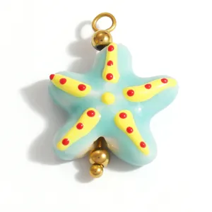 Macro detail shot of a blue enamel starfish pendant with red dots and gold metal