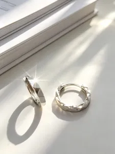 Macro dettagliata di orecchini a cerchio in argento sterling S925 sfaccettati al sole