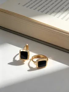 Dettaglio di eleganti orecchini a cerchio quadrati in oro con smalto nero pregiato