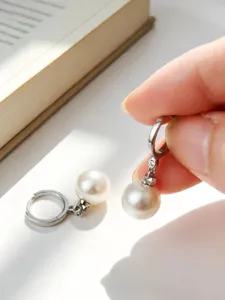 Dettaglio ravvicinato di eleganti orecchini a cerchio in argento S925 con grandi perle
