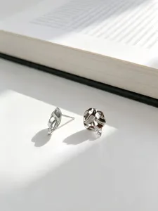 Detalle de pendientes de plata S925 con superficie texturizada y piedras de circón brillante.