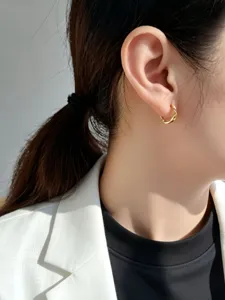 Detailaufnahme eines minimalistischen goldenen Mobius-Ohrrings, getragen von einem Model