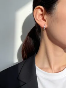 Close-up van minimalistische zilveren V-vormige oorring op model