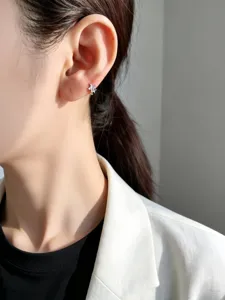 Primer plano de un pendiente de estrella de 6 mm en plata S925 en la oreja de la modelo