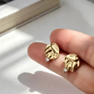 Elegantes pendientes dorados con textura martillada y pequeños circonitas claras.
