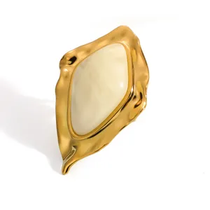 Close-up of vintage irregular geometric gold-plated earring with cream resin inlay